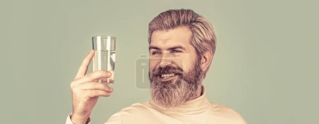 Téléchargez les photos : Un homme buvant dans un verre d'eau. Concept de soins de santé, mode de vie, gros plan. Souriant mâle tenant verre transparent dans sa main. - en image libre de droit