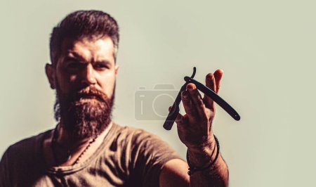 Photo for Mens haircut. Man in barbershop. Handsome bearded hairdresser is holding a straight razor while barbershop. - Royalty Free Image