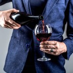 Waiter pouring red wine in a glass. Sommelier man, degustation, winery, male winemaker.