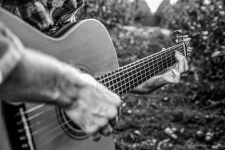 Téléchargez les photos : Mans mains jouant de la guitare acoustique, fermer. Guitares acoustiques jouant. Concept musical. Noir et blanc. - en image libre de droit