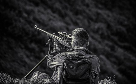 Hunting period. Hunter is aiming. The man is on the hunt. Hunter with shotgun gun on hunt. Deer hunt. Hunter in camouflage clothes ready to hunt with hunting rifle. Hunter man. Black and white.