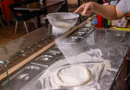 Sift flour by sieve with the flour for beating up dough, pizza. Hands to rub flour. Process of making pizza. Professional chef in a kitchen prepares dough from flour to cook Italian pasta, pizza.