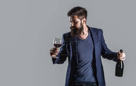 Rotwein im Glas. Sommelier, Degustator, Weingut. Mann hält Flasche mit Champagner. Der Mann im Anzug stößt mit einem Glas Rotwein an. Rotwein in der Flasche, Weinglas.