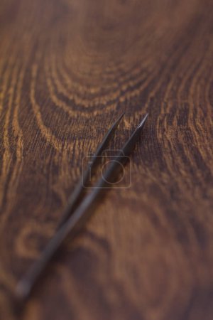 Téléchargez les photos : Brucelles d'extension de cils argentés gros plan sur un fond en bois - en image libre de droit