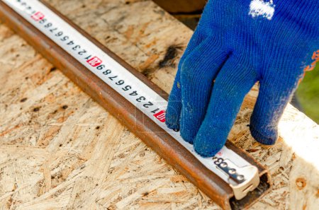 Téléchargez les photos : Un travailleur donne un gant avec un ruban à mesurer. Construction - en image libre de droit