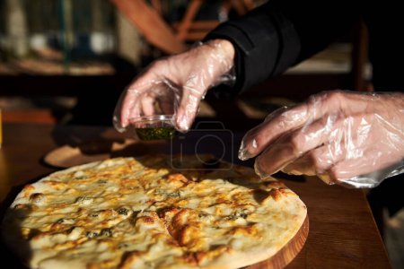 Une délicieuse pizza ronde sur un plateau en bois couché sur la table.Mains ramasser une tranche de pizza italienne traditionnelle à quatre fromages dans un restaurant extérieur.Collation simple.Aliments malsains.Règles nutritionnelles. Gros plan