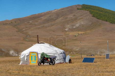 Nomadic persons yurt in rural Mongolian landscape. Ger tent on the foothill with beautiful mountains in the background on the sunny day.