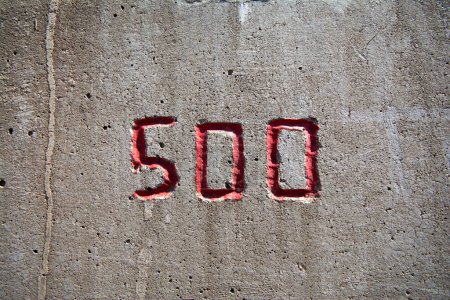 Foto de El número 500 tallado en una pared de hormigón en rojo - Imagen libre de derechos