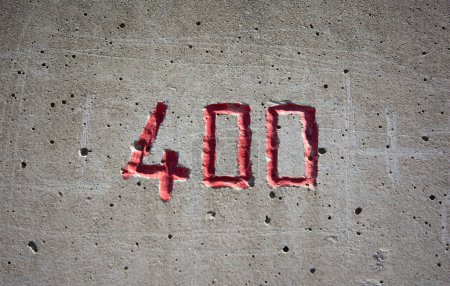 el número 400 tallado en una pared de hormigón en rojo
