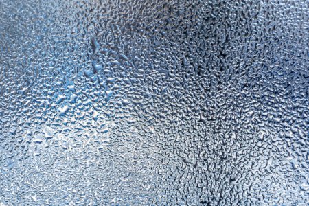 Das Bild zeigt eine detaillierte Ansicht einer Oberfläche, die dicht mit winzigen Wassertröpfchen bedeckt ist. Die komplizierten Muster, die durch die Tröpfchen geformt werden, erzeugen eine silberfarbene Optik, die die Textur und Details hervorhebt.