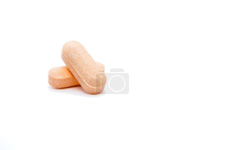 Vor einem schlichten weißen Hintergrund werden zwei orangefarbene Tabletten übereinander gelegt. Die Tabletten haben eine strukturierte Oberfläche und wirken mittelgroß..