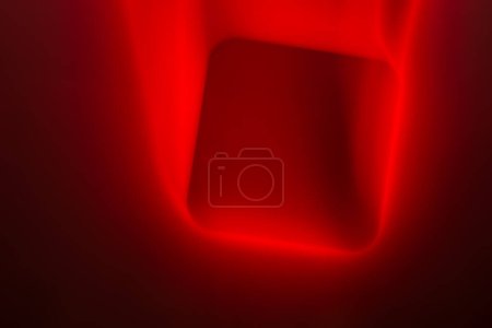 An abstract image showcasing a bold, luminous red square set against a deep red and black background. The edges of the square are soft, blending into the surrounding colors, creating a striking visual effect.