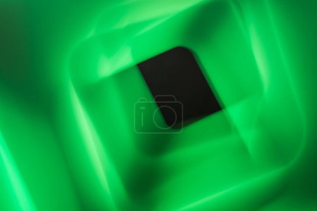 Foto de Una llamativa imagen abstracta dominada por vivos colores verdes con un cuadrado negro central. Las áreas verdes circundantes muestran una mezcla dinámica de luz y sombras, dando a la imagen una sensación de profundidad y movimiento.. - Imagen libre de derechos