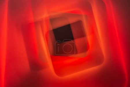 A striking abstract image featuring red, orange, and black hues with geometric shapes. The soft focus and overlaying colors create a sense of depth and motion.