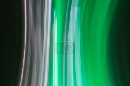 Une image abstraite présentant des stries verticales de lumière dans des tons de vert, blanc et noir. Les sentiers lumineux créent un sentiment de mouvement et de fluidité, rappelant les lumières capturées dans la photographie de mouvement
