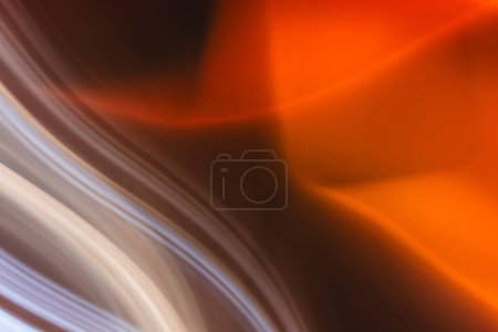A blur of orange and brown shades flowing together, creating an abstract, wave-like effect. The image has a sense of dynamic movement.