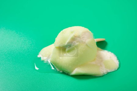 Foto de Forma de manzana verde medio derretida y palomitas de sabor sobre fondo verde - Imagen libre de derechos