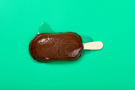 Foto de Chocolate exterior con leche y arándanos sabores paleta en un proceso de fusión sobre fondo verde - Imagen libre de derechos