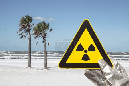 Foto de Señal de advertencia de radiación nuclear frente a una playa - Imagen libre de derechos