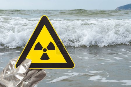 Téléchargez les photos : Panneau d'avertissement de rayonnement nucléaire devant une composition horizontale de l'océan - en image libre de droit