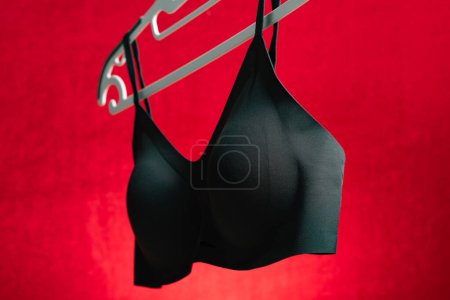 Photo for Side view black bra hanging on red background - Royalty Free Image