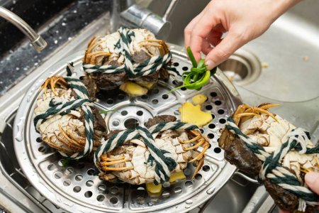 Téléchargez les photos : Dame mettre des crabes à un rack fumant - en image libre de droit