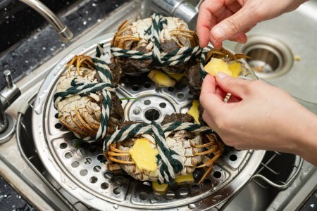 Téléchargez les photos : Dame préparant des crabes et sur la vapeur de cuisson - en image libre de droit