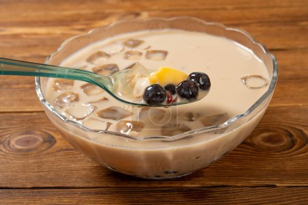 angle view bowl of milktea flavor syrup mixed with grass jelly and mangoes and peach gum and tapiocas and red beans and guiling jelly etc. at horizontal composition