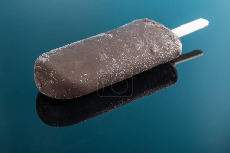 Schokolade äußeres Eis am Stiel auf blauem Hintergrund mit Reflexion