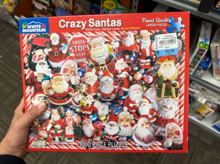 Foto de New Hope, Minnesota - 6 de noviembre de 2022: Hand sostiene un rompecabezas de 1000 piezas de Crazy Santas by White Mountain mientras compra - Imagen libre de derechos