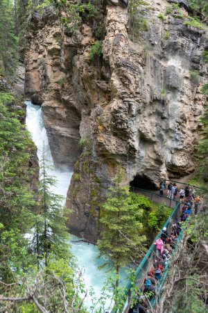 Téléchargez les photos : Alberta, Canada - 10 juillet 2022 : Des foules de touristes attendent pour prendre des photos à la cascade des chutes inférieures dans le canyon Johnston - en image libre de droit