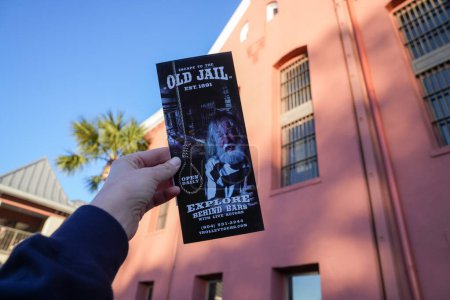Photo for St. Augustine, Florida - December 28, 2022: Tourist holds up a brochure advertisting tours for the Old Jail - Royalty Free Image