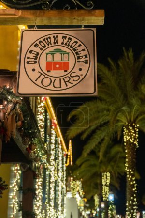 Photo for St. Augustine, Florida - December 30, 2022: Sign for the Old Town Trolley Tours booth, during the Nights of Lights. Christmas lights bokeh in background - Royalty Free Image