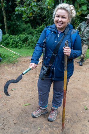 Téléchargez les photos : Femme en randonnée gorille en Ouganda tient une machette en prépration pour sa randonnée à voir gorilles de montagne - en image libre de droit
