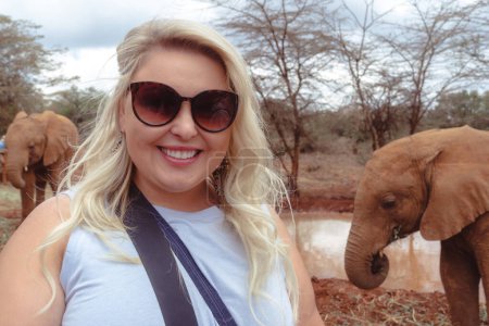 Photo for Tourist woman caucasian poses with elephants behind her - Kenya, Africa - Royalty Free Image