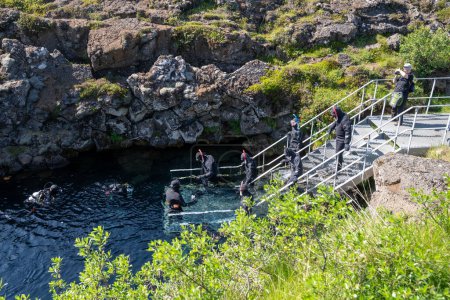 Photo for Thingvellir National Park, Iceland - July 9, 2023: Tourists prepare to snorkel between the two tectonic plates at the steps to enter the cold water at Silfra - Royalty Free Image