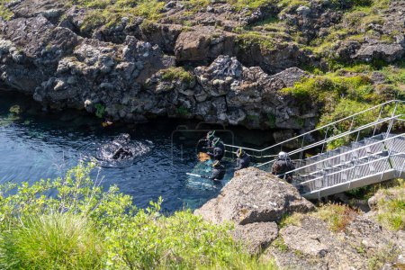 Foto de Thingvellir National Park, Islandia - 9 de julio de 2023: Los turistas se preparan para bucear entre las dos placas tectónicas en los escalones para entrar en el agua fría - Imagen libre de derechos