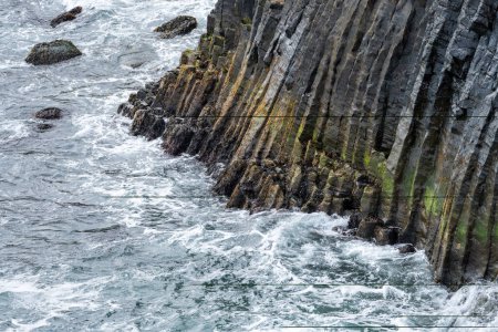Foto de Hermosas columnas de basalto en la orilla de Islandia, en Arnarstapi como las olas se estrellan - Imagen libre de derechos