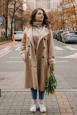 Téléchargez les photos : Concept de style de vie Pologne et les villes de voyage à Varsovie. Femme ont un beau bouquet de tulipes jaunes debout à l'extérieur à Varsovie. - en image libre de droit