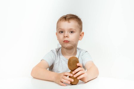Photo for A Boy having fun on studio grey background. Cute kid with kiwi isolated. - Royalty Free Image