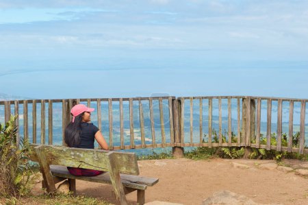 Eine Person sitzt auf einer Bank und blickt von einem hohen Aussichtspunkt im Naturreservat des Vulkans Mombacho auf die weite Landschaft.