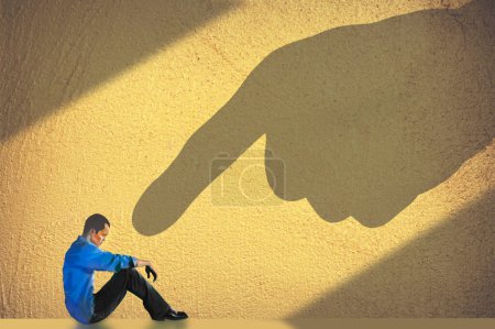 Photo for Blame is illustrated with a shadowy finger pointing right at him as he sits on the floor alone in a room in a 3-d illustration. - Royalty Free Image
