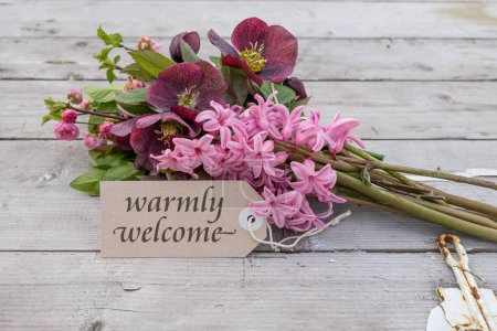 Bouquet with pink hyacinths, Christmas roses and card with English text: warmly welcome
