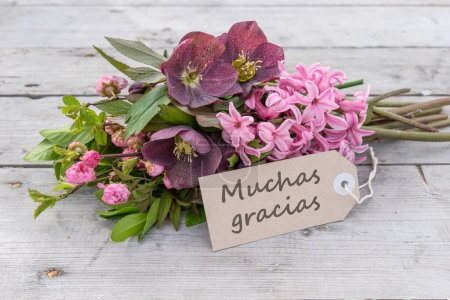 Grußkarte mit Bouquet aus rosa Hyazinthen, Weihnachtsrosen und Karte mit spanischem Text: Danke