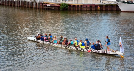 Photo for Cleveland, OH - July 3, 2022: A dragon boat, a type of large kayak for a team of paddlers, rows by on the Cuyahoga River in downtown Cleveland Ohio on a summer morning. - Royalty Free Image
