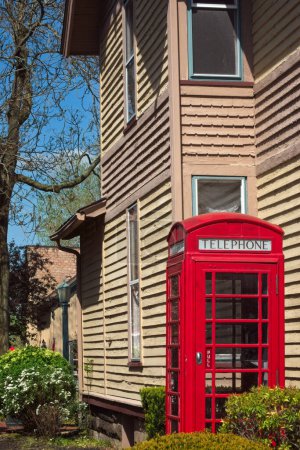 A vintage British-style phone booth stands next to an old house in a northeast Ohio village near Cleveland.