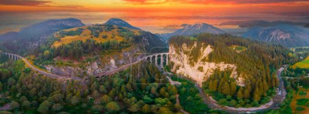 Téléchargez les photos : Vue aérienne du train qui traverse la célèbre montagne de Filisur, en Suisse. Landwasser Viaduc patrimoine mondial avec train express dans les Alpes suisses - en image libre de droit