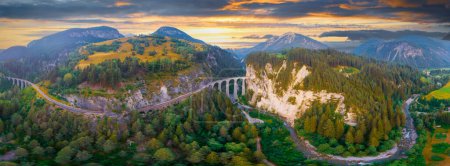 Téléchargez les photos : Vue aérienne du train qui traverse la célèbre montagne de Filisur, en Suisse. Landwasser Viaduc patrimoine mondial avec train express dans les Alpes suisses - en image libre de droit