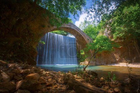 Die alte steinerne Bogenbrücke zwischen zwei Wasserfällen in Palaiokaria, Präfektur Trikala, Thessalien, Griechenland.
