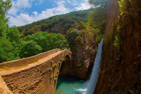 Die alte steinerne Bogenbrücke zwischen zwei Wasserfällen in Palaiokaria, Präfektur Trikala, Thessalien, Griechenland.